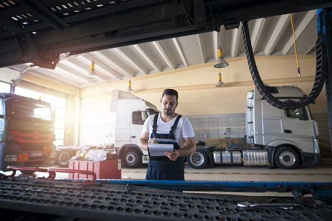 Truck repair shop. Vehicle serviceman with controlling trucks that need maintenance and service.